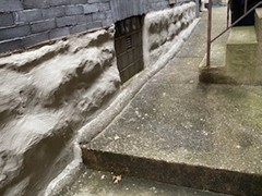 To begin correcting this problem for him, we were able to pressure wash off the algae, repair holes in the foundation, build a birm along the seam of sidewalk, and resurface the entire area of sandstone foundation.